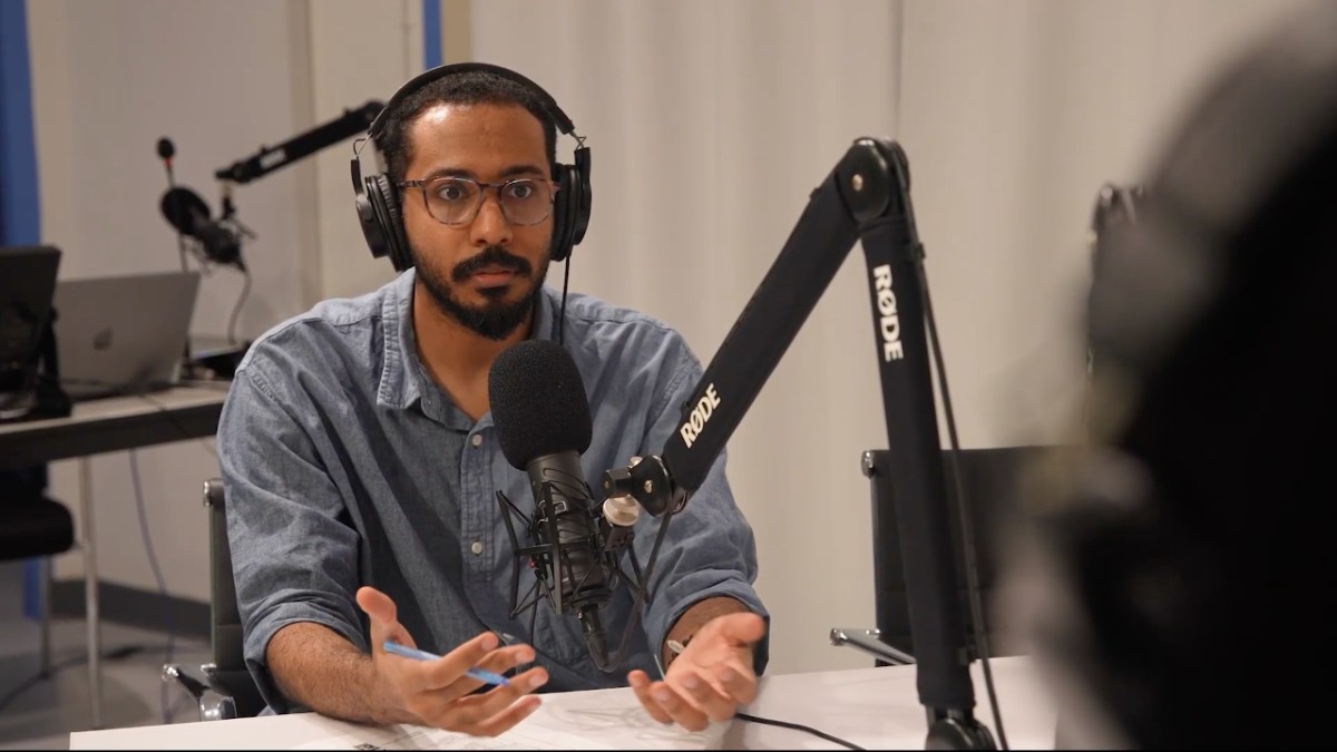 Abu - a media support associate - sitting at podcasting microphone in Studio B, Macy 259.